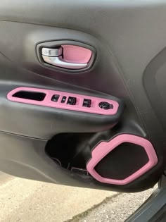 the interior of a car with pink trims and black door handles, including an electronic device