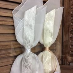 three white bags with lace on them are sitting in front of a wooden wall and window