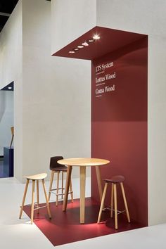 two wooden stools sitting next to a round table on top of a red floor