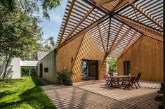 an outdoor patio with tables and chairs under a pergolated roof over looking the back yard