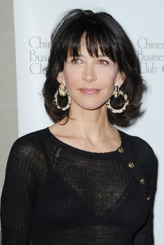 a woman with black hair wearing large earrings