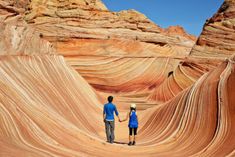 two people standing in the middle of an area that looks like wavy rocks and sand