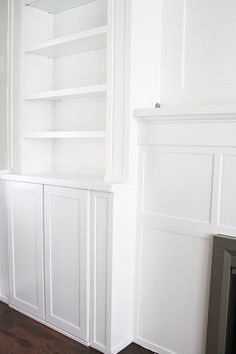 a white bookcase in the corner of a room with a fire place and fireplace