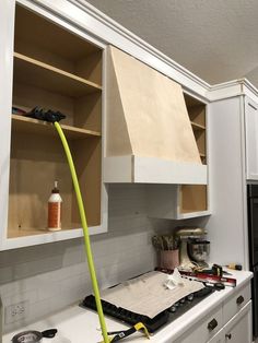 a kitchen with white cabinets and tools on the counter top in front of an oven