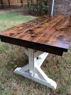 a wooden table sitting on top of a grass covered field next to a brick wall