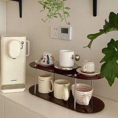 there is a coffee maker and cups on the shelf next to each other in this room