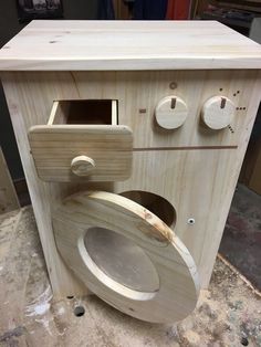 a wooden toilet sitting on top of a table next to a wall mounted device with multiple knobs