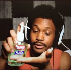 a man with headphones on holding up a bottle of mouthwash