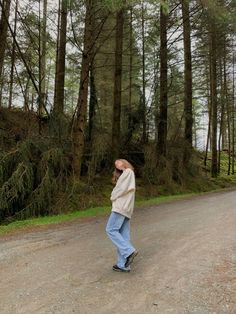 a man standing on the side of a road in front of trees