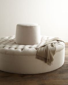 a round ottoman with a blanket on it