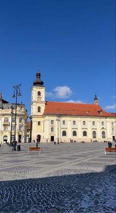 an old building with a clock tower in the center and people sitting on benches around it