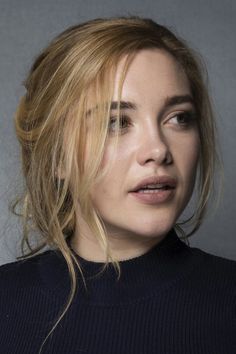 a woman with blonde hair wearing a black turtle neck sweater looking off to the side