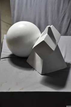 an egg sitting on top of a table next to a white object in the shape of a house