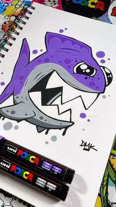 a drawing of a shark with its mouth open and eyes wide open next to markers