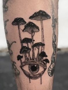 a tattoo with mushrooms and an eye on it