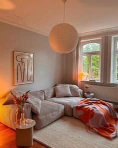 a living room filled with furniture and a large window covered in light colored blankets on top of a hard wood floor