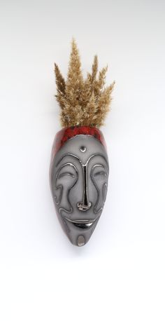 a mask with feathers sticking out of it's mouth on a white background,