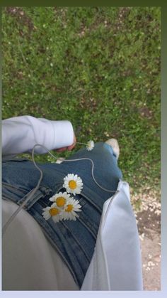 the back end of a person's jeans with daisies on it and an electronic device in their lap