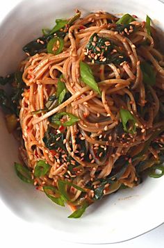 a white bowl filled with noodles and greens