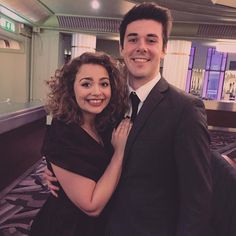 a man in a suit and tie standing next to a woman wearing a black dress