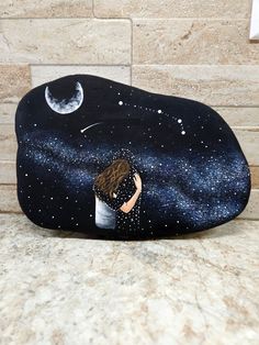 there is a rock with a painting on it that has a woman hugging her head