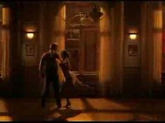 a man and woman dancing in an old fashioned room at night time with lights on