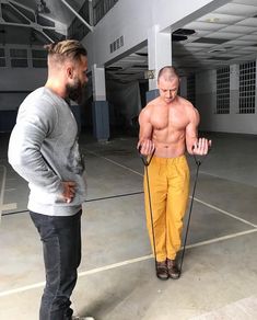 two men standing in an empty parking lot with one holding a rope and the other looking down