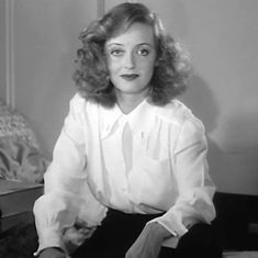 black and white photograph of a woman sitting on a chair with her hands in her pockets