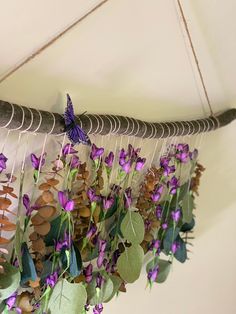 purple flowers and green leaves hang from a metal rod with a butterfly on it's wing