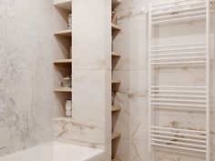 a bathroom with marble walls and flooring next to a white bathtub in front of a radiator