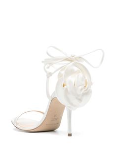 a white shoe with a flower on the heel and satin fabric around the ankle, which is