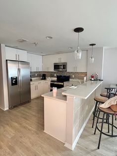 a kitchen with white cabinets and an island in the middle is shown, along with four bar stools