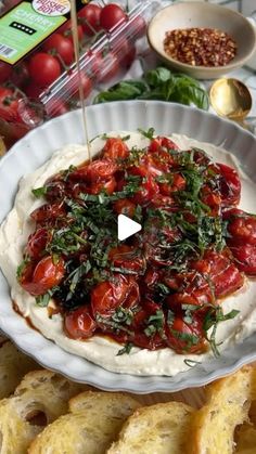 an image of a plate of food on a table with breads and tomatoes in the background