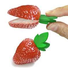 two strawberries being cut into smaller pieces with green leaves on each side and the other half