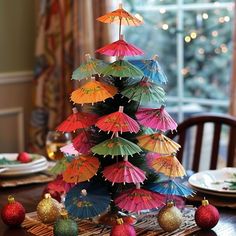 a christmas tree made out of umbrellas on top of a wooden table with ornaments around it