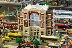 a toy model of a building with cars and buses on display in front of it