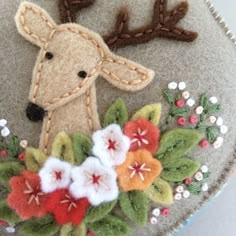 a close up of a felt decoration with flowers and a deer's head on it