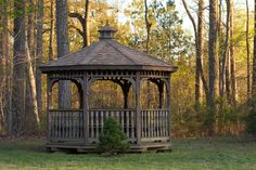 a wooden gazebo in the middle of a wooded area