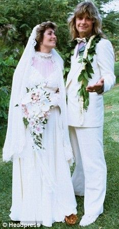 a man and woman dressed in white standing next to each other on a grass covered field