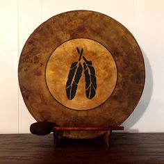 a wooden plate with an image of two feathers on the front and one leaf on the back