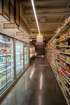 an empty grocery store aisle with shelves full of food and drinks on the sidelines