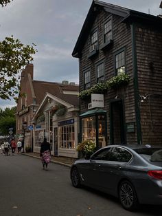 a car parked on the side of a road next to a tall wooden building with windows