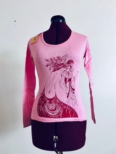 Deadstock 70s pullover t-shirt with Audrey Beardsley screen print art in pink. It has a scooped neckline, a straight hem and art on the front and back.   Material: Cotton Brand: Chandra  Origin: India Color/print: Pink Era: 70's  Size:  Tag says Large,  could fit M-L Approximate Measurements  Bust: 34"-40" Waist: 30"-36" Length: 20"  Condition: excellent unused with tags attached  Bust-taken from under the arm to under arm laying flat  Sleeves-taken from under the arm to sleeve end  Waist-taken Fitted Pink Printed T-shirt, Retro Pink Printed T-shirt, Fitted Vintage Print T-shirt For Spring, Vintage Stretch T-shirt With Graphic Print, Pink Long Sleeve Stretch T-shirt, Pink Long Sleeve T-shirt With Graphic Print, Vintage Stretch Tops With Graphic Print, Retro Long Sleeve Tops With Screen Print, Fitted Vintage Tops With Graphic Print