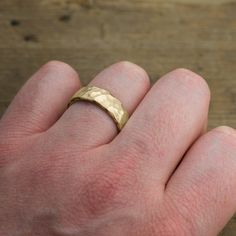 a person's hand with a gold ring on it