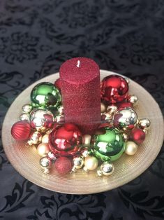 a red candle sitting on top of a plate filled with ornaments