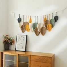 a wooden cabinet sitting in front of a wall hanging with tassels on it