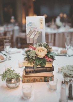 a table topped with books and flowers on top of each other next to candle holders