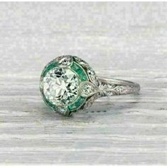 an old - fashioned diamond and emerald engagement ring with filigrees on the sides