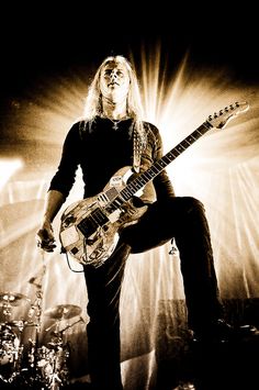 a man with long hair playing an electric guitar