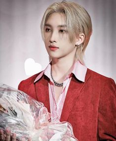 a man holding a bunch of flowers and a heart shaped object in front of him